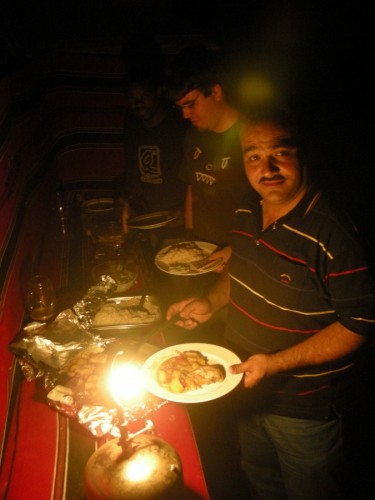 The other three tourists load up their plates by the glow of gas camping lamps