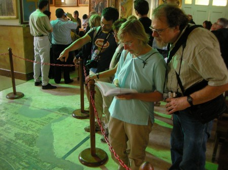 Groups of tourists search for familiar sites in the mosaic, while a baptism is carried out in the background